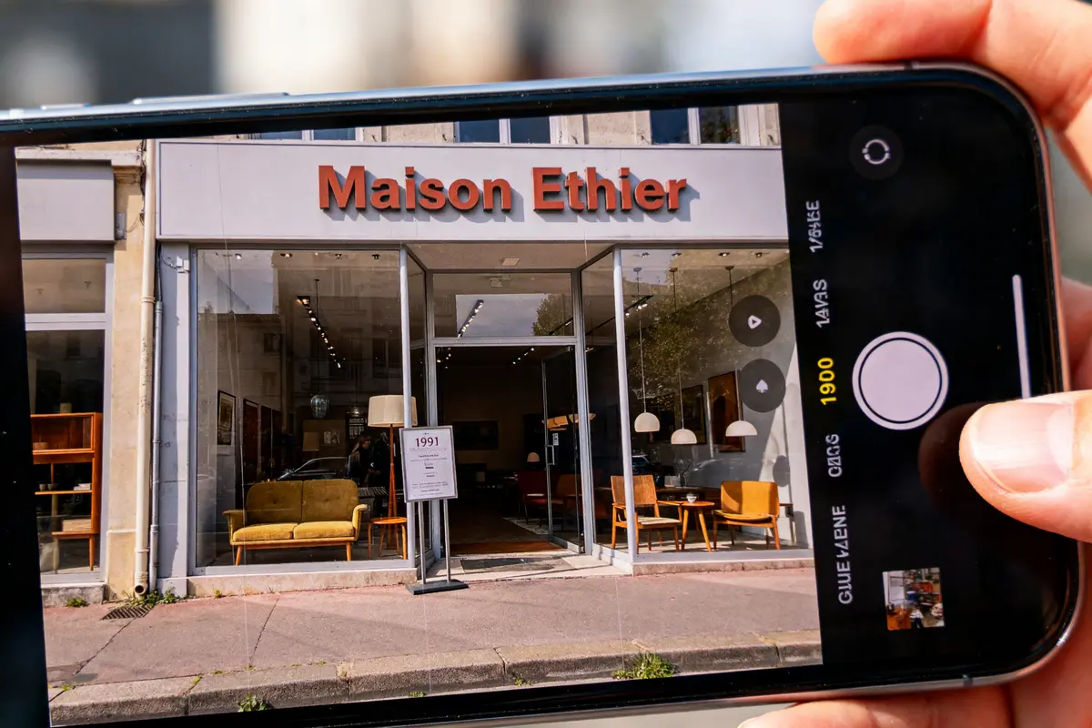 Vitrine de magasin "Maison Ethier" photographiée à travers un smartphone, meubles modernes exposés.