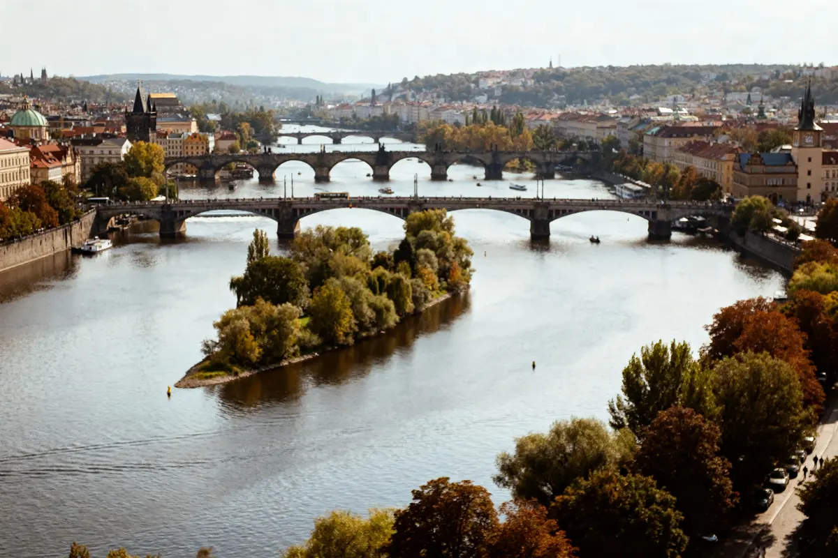 Ponts historiques sur le fleuve Prague avec végétation et bâtiments en arrière-plan