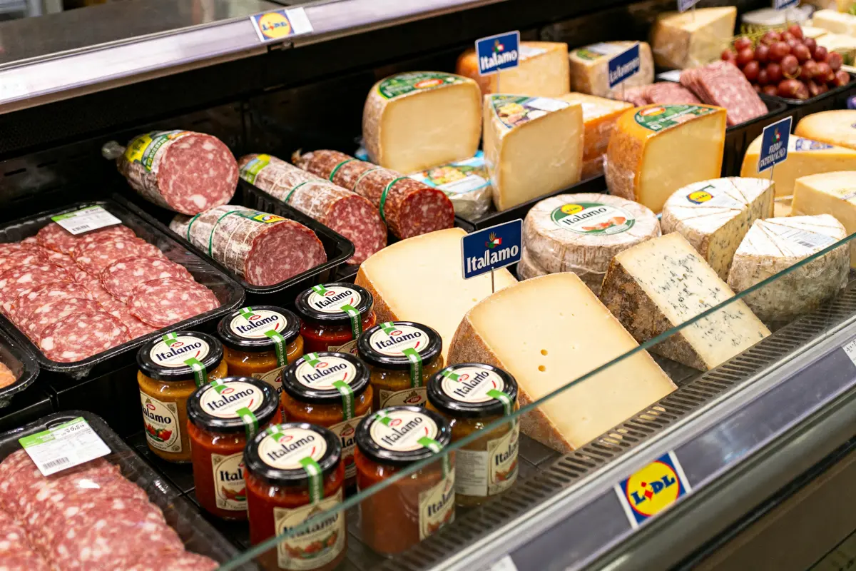 Produits alimentaires italiens Lidl avec fromages, charcuteries et sauces dans un rayon réfrigéré.