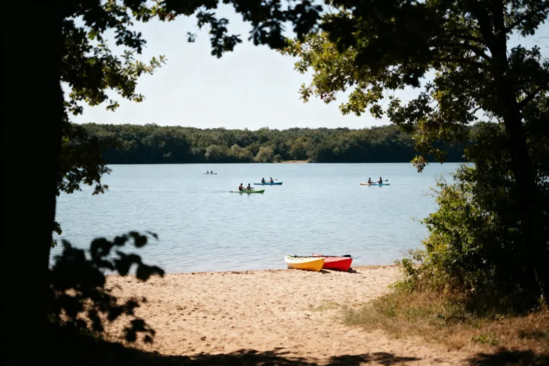 Des kayaks sur la plage et sur l'eau calme du lac du Tolerme