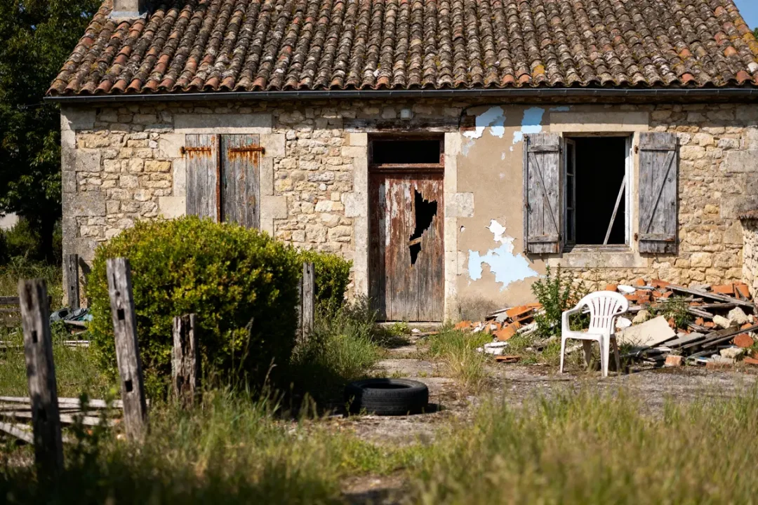 Vieille maison à donner gratuitement avec façade abîmée et jardin en friche
