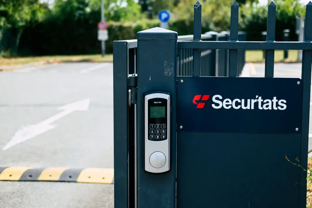 Clôture avec clavier d'entrée sécurisé, logo mon portail Securitas visible devant un parking