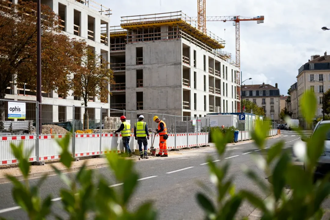 Travailleurs sur un chantier immobilier ophis Clermont Ferrand avec bâtiments en construction