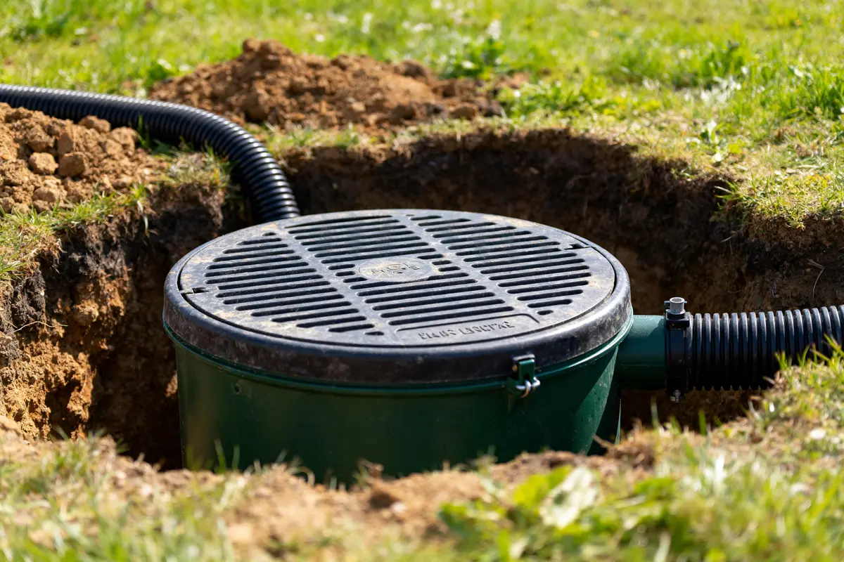 Couvercle de ventilation fosse septique avec tuyau noir dans un terrain dégagé.