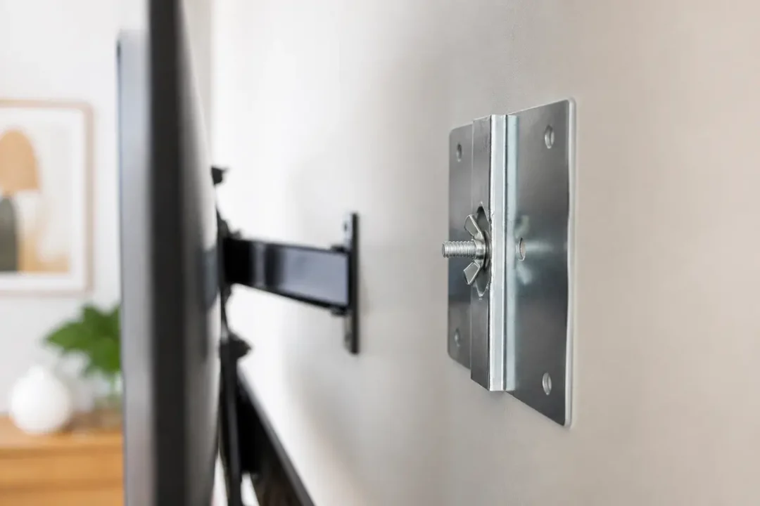 Supports TV fixés au mur avec bras pivotant métallique, intérieur moderne en arrière-plan flou.